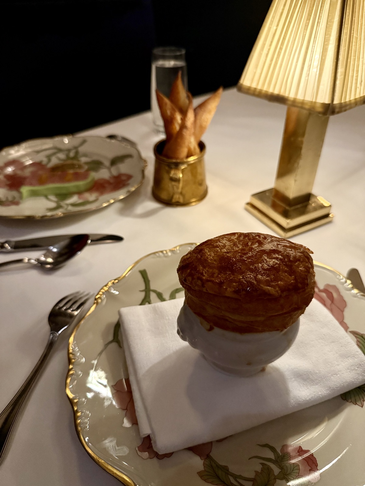Garlic soup en croute at Le B., with preserved white truffle, sherry, and a domed puff pastry lid, served on floral Herend-style china